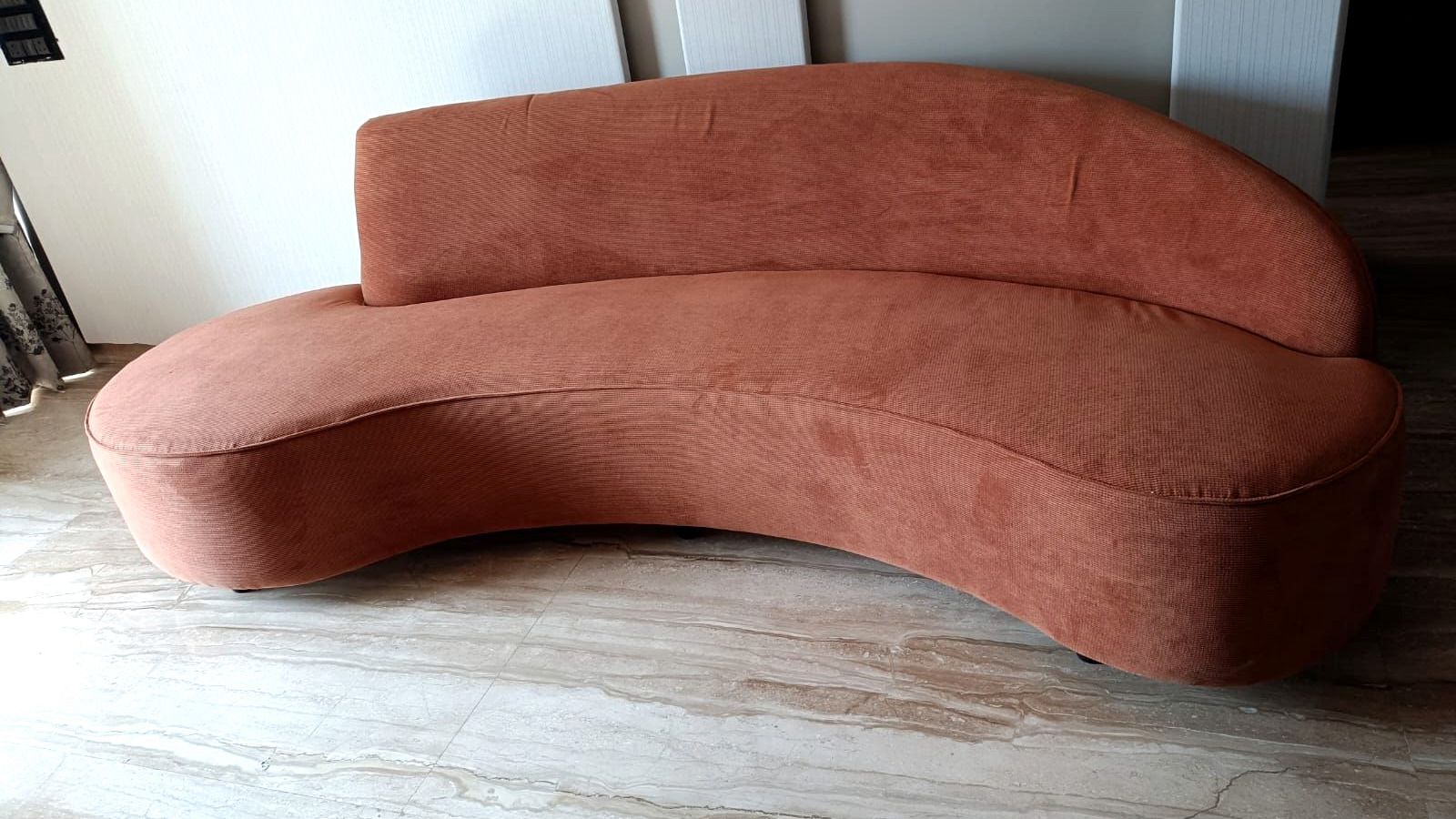 Curved rust sofa in a pale, calm interior.